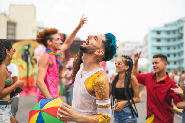 A foto mostra pessoas aproveitando o Carnaval na rua, com muitas cores vibrantes e brilhos.